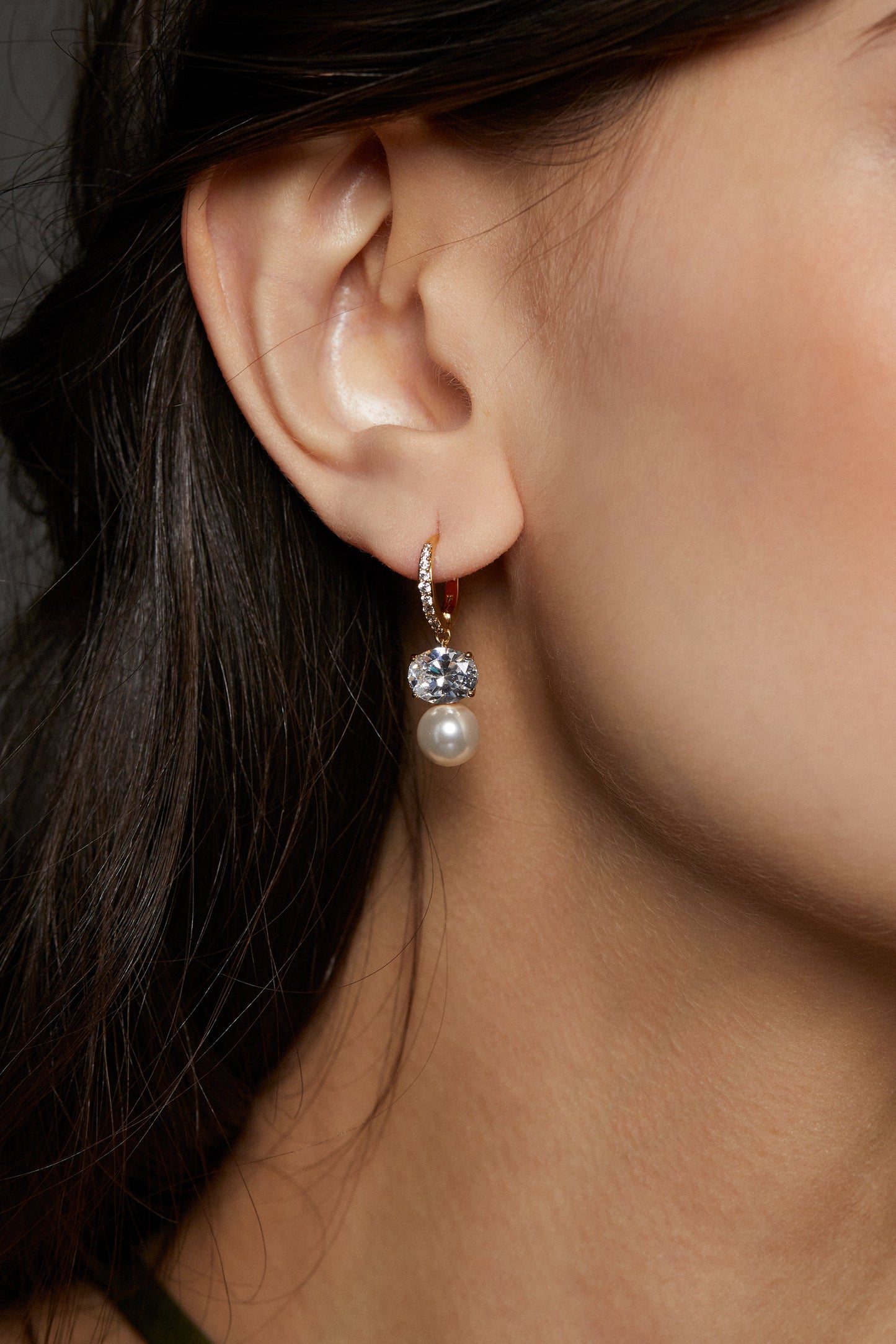 NATURAL BEAUTY DROP EARRING ON MODEL. IT IS A CLOSE UP IMAGE OF HER EAR WITH HER DARK HAIR PULLED BACK. 