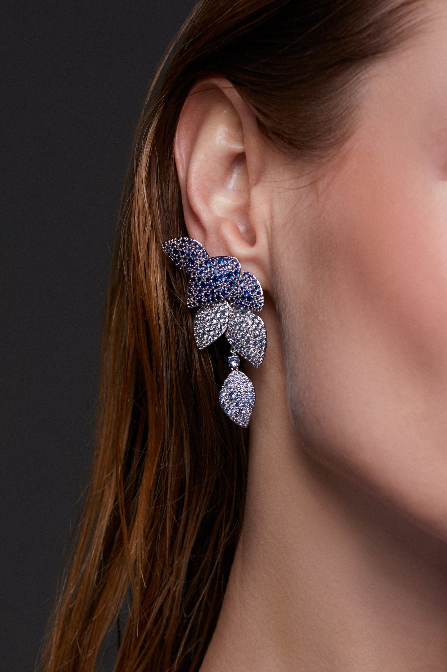 MODEL WEARING STARLET BLUE LEAF LINEAR EARRINGS. IT IS A CLOSE UP TIGHT CROP OF HER EAR. 