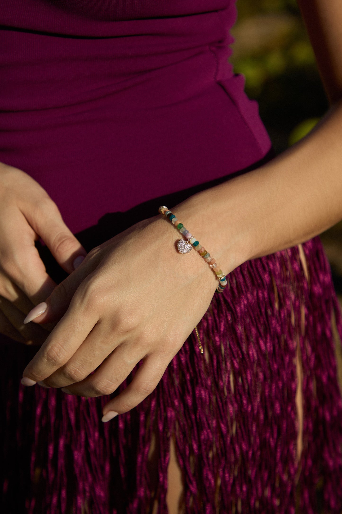 CLOSE UP OF A MODEL’S HANDS IN FRONT OF HER, AS SHE WEARS A FRINGE COVERUP AND THE BEADS OF PARADISE HEART BOLO BRACELET