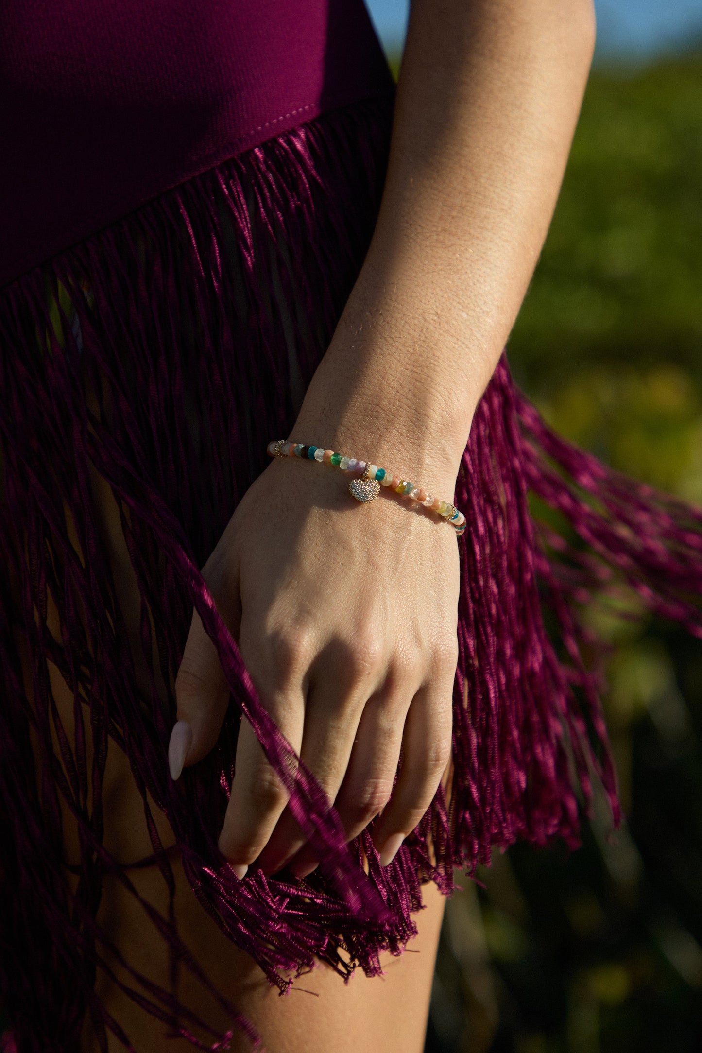 CLOSE UP OF A MODEL’S HAND AT HER SIDE, AS SHE WEARS A FRINGE COVERUP AND THE BEADS OF PARADISE HEART BOLO BRACELET