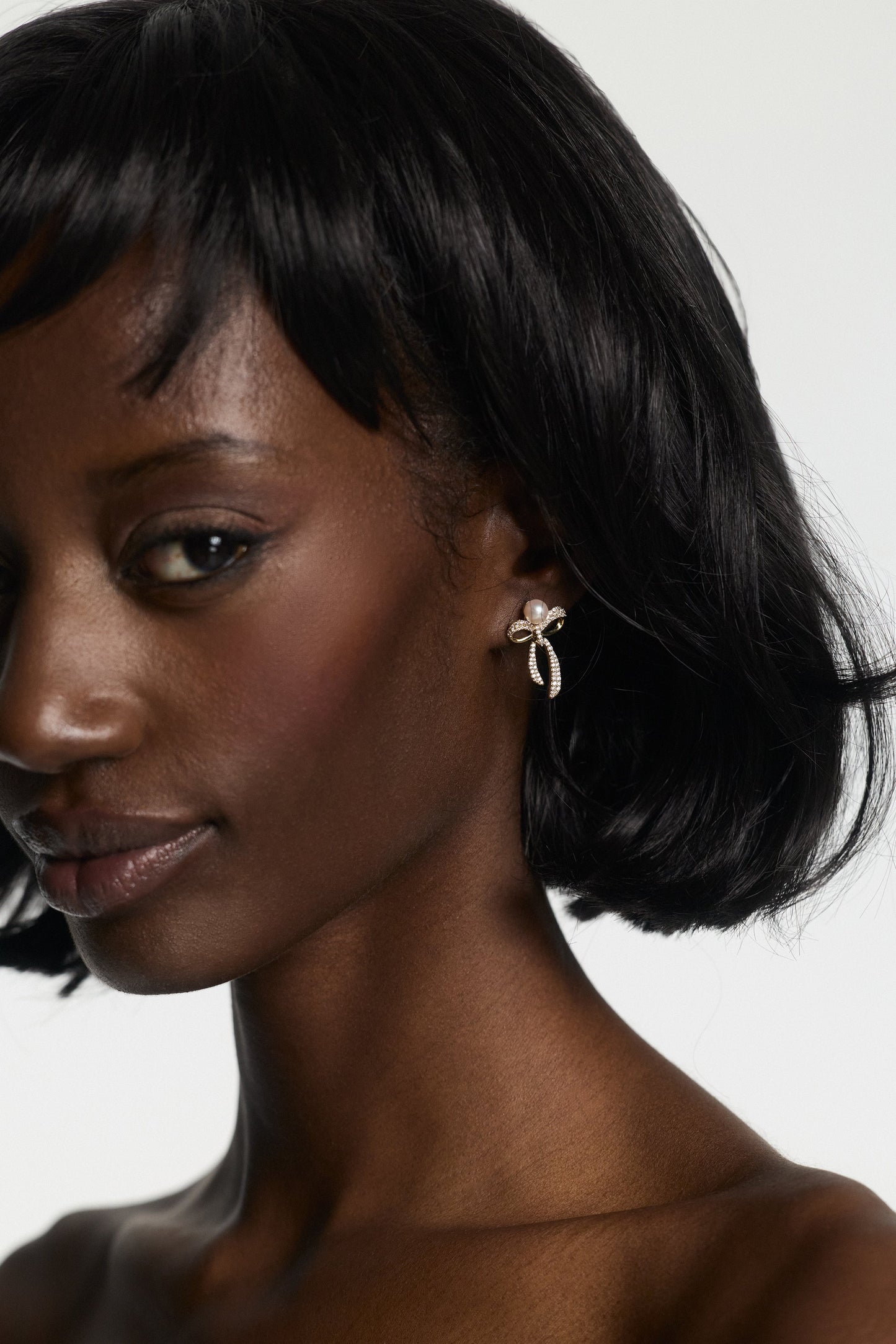CLOSE UP OF A MODEL WITH SHORT HAIR LOOKING AT THE CAMERA, WEARING NADRI’S EROS SMALL BOW AND PEARL EARRINGS