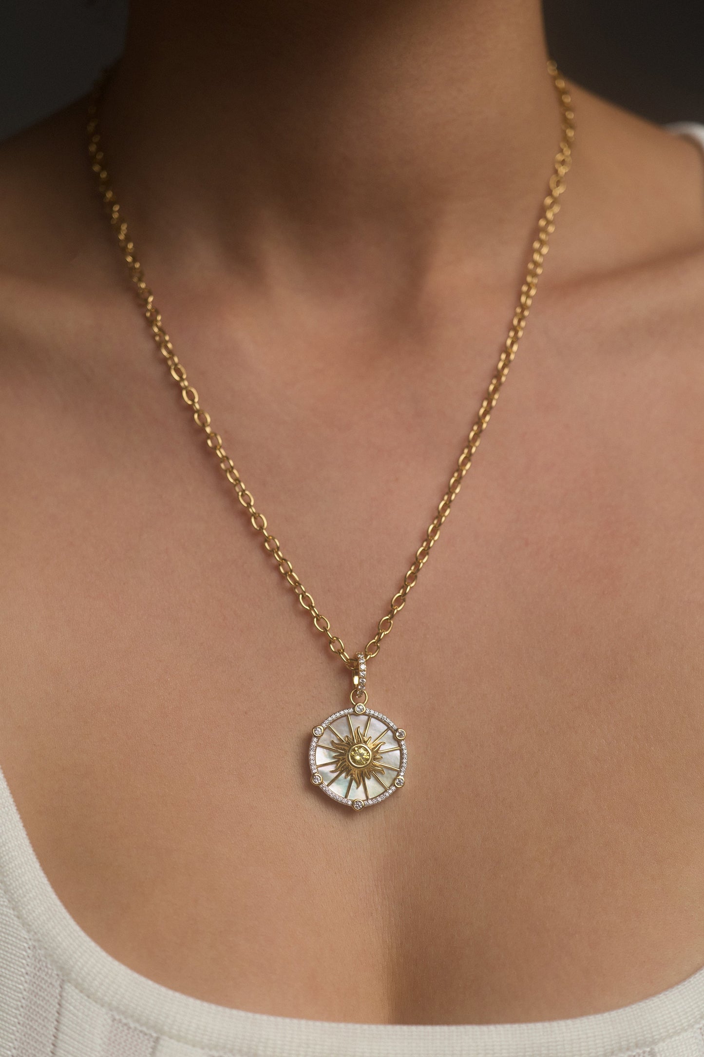 CLOSE UP OF A MODEL’S NECKLINE WEARING THE GLOBE TROTTER SUN PENDANT NECKLACE