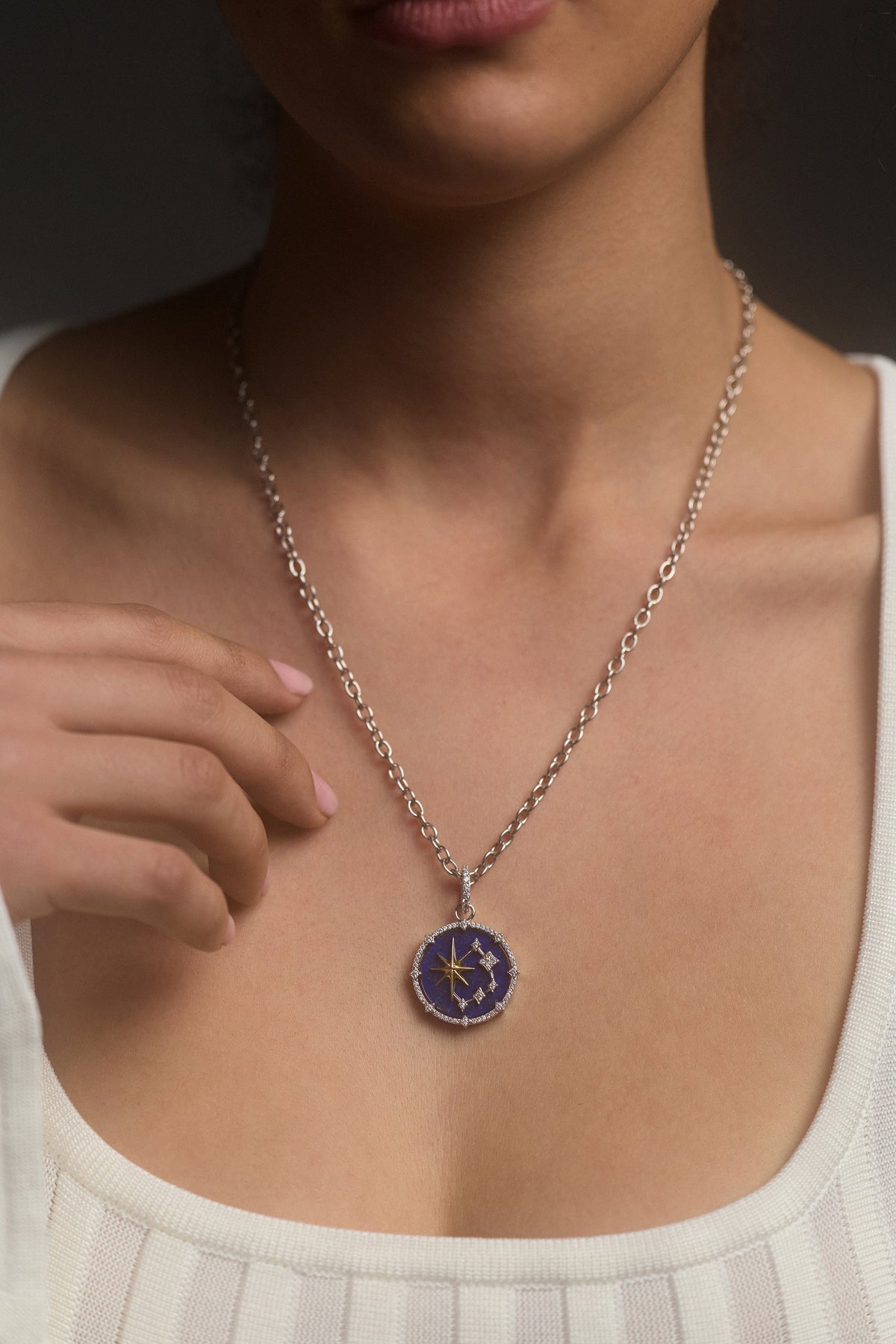 CLOSE UP OF A MODEL’S CHEST, WEARING A WHITE TOP AND THE GLOBE TROTTER STARS PENDANT NECKLACE