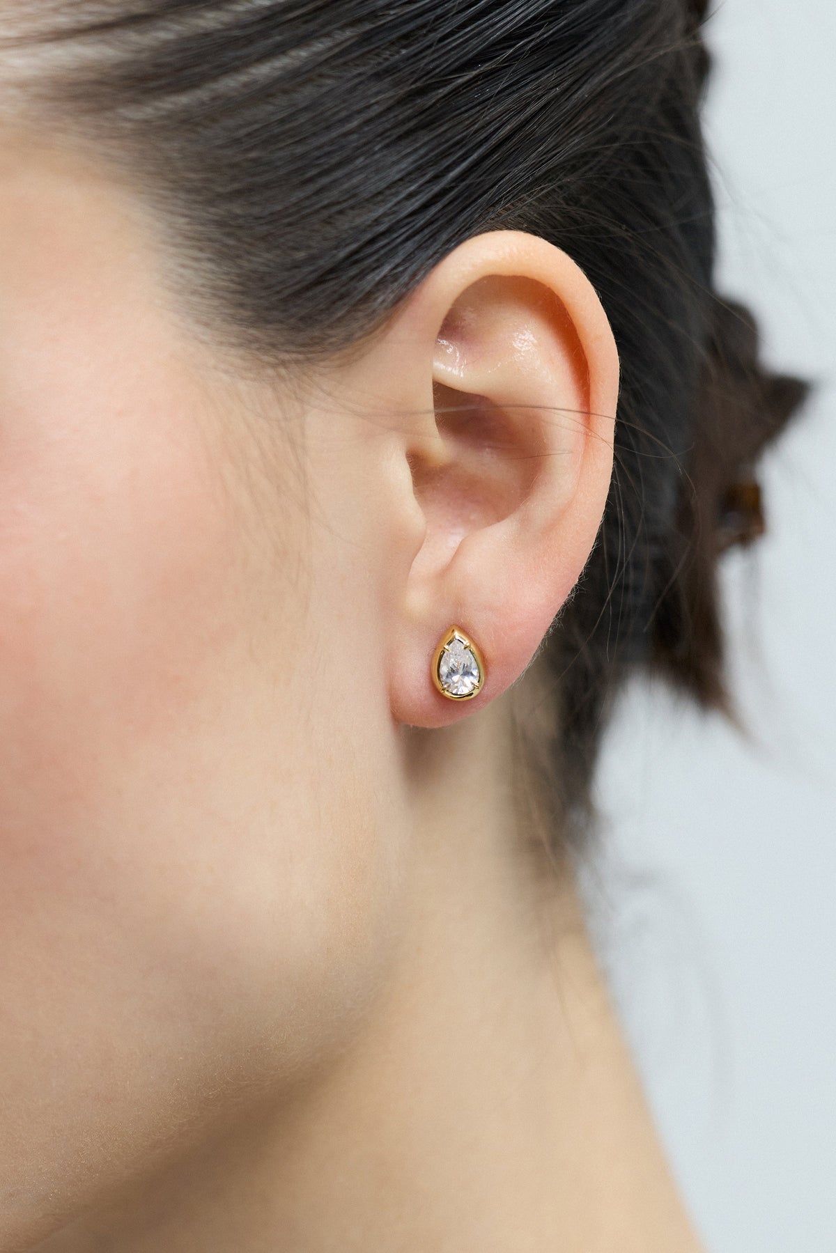 CLOSE UP OF A MODEL’S EAR AS SHE WEARS THE PEAR STUD FROM THE DELANCEY STUD SET OF EARRINGS