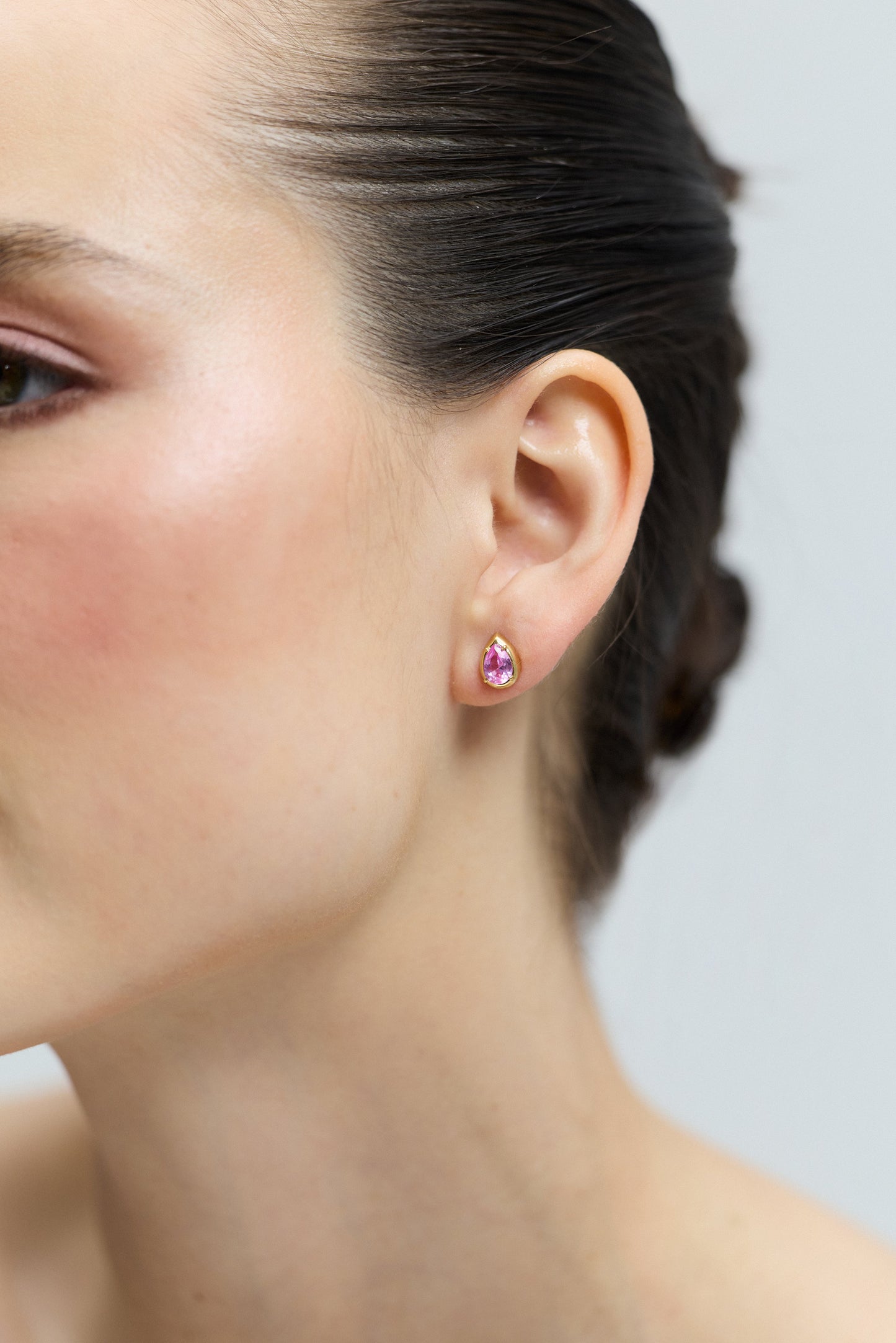 CLOSE UP OF A MODEL’S EAR WEARING THE PEAR STUD FROM THE DELANCEY PINK STUD SET OF EARRINGS