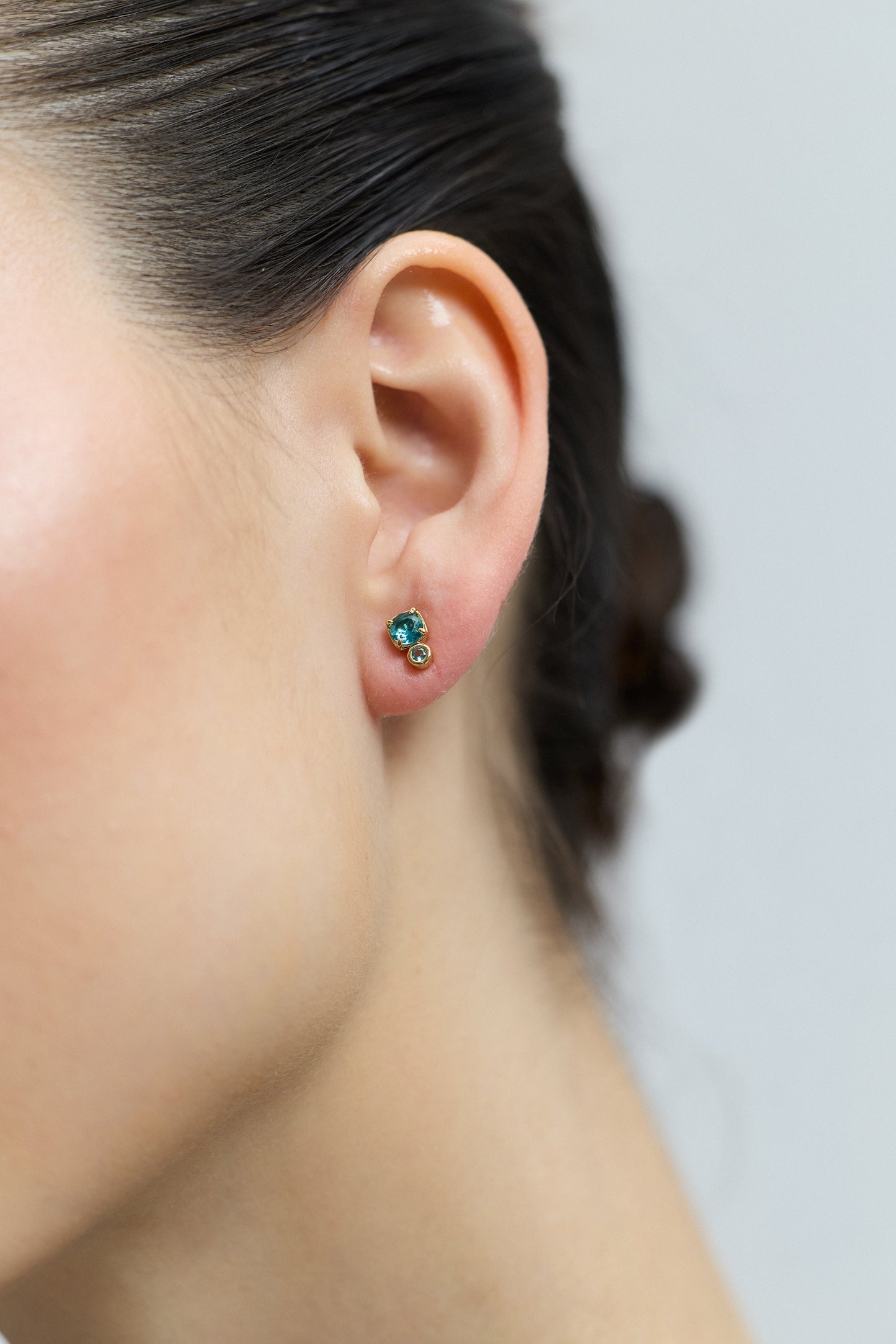 CLOSE UP OF A MODEL’S EAR WEARING THE DOUBLE STONE STUD FROM THE DELANCEY AQUA STUD SET OF EARRINGS