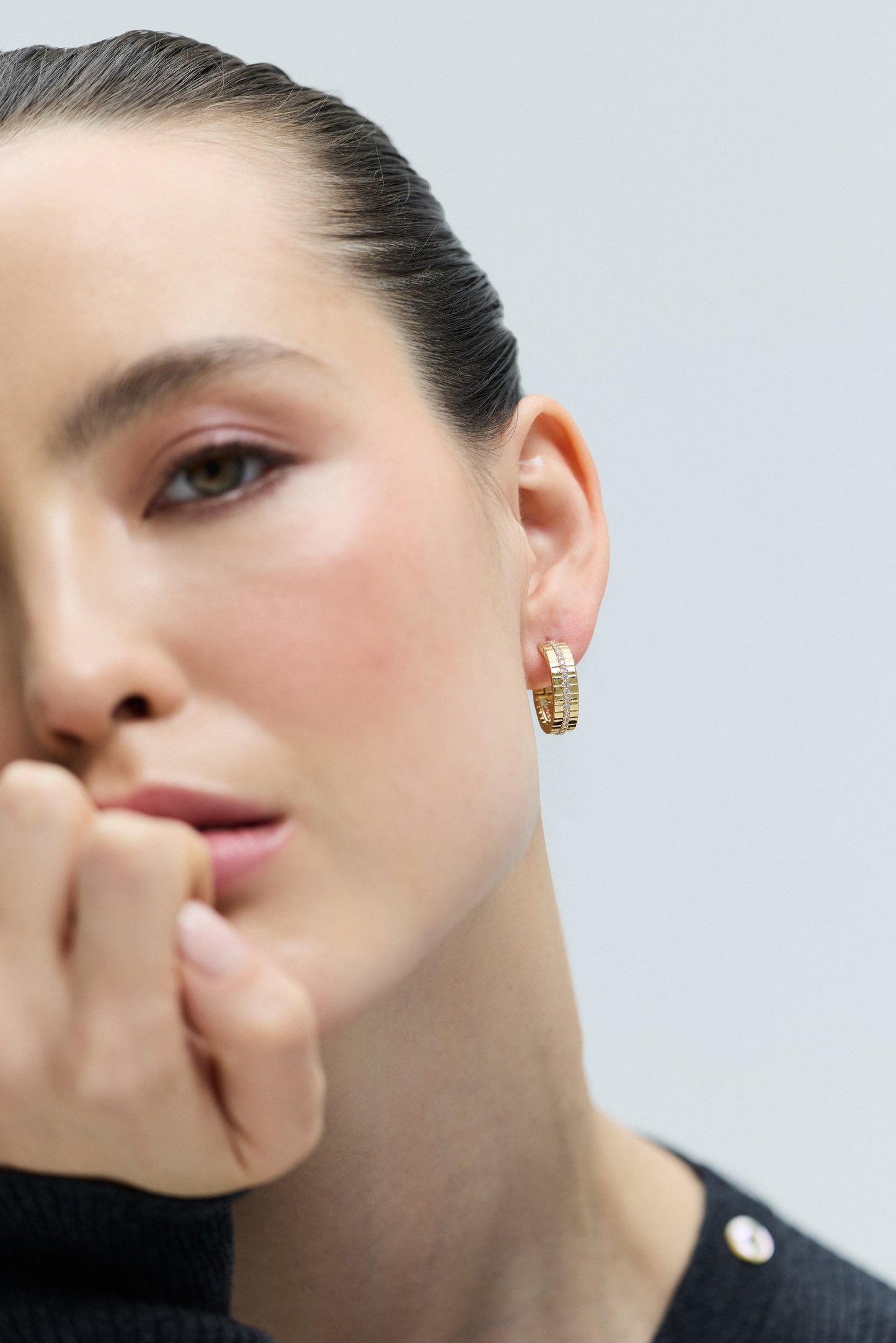 CLOSE UP OF HALF OF A MODEL’S FACE WITH HER EAR IN FOCUS, AS SHE WEARS THE DELANCEY PAVE STRIPE HOOP EARRINGS