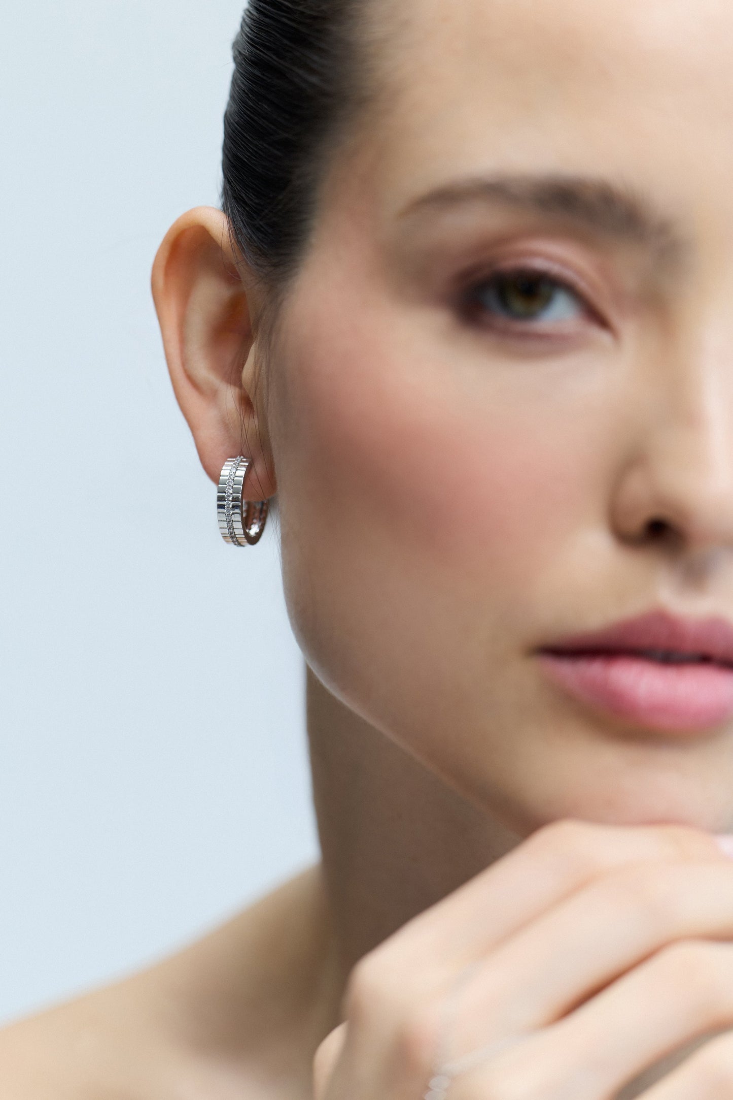 HALF OF A MODEL’S FACE WITH HER EAR IN FOCUS, AS SHE WEARS THE DELANCEY PAVE STRIPE HOOP EARRINGS