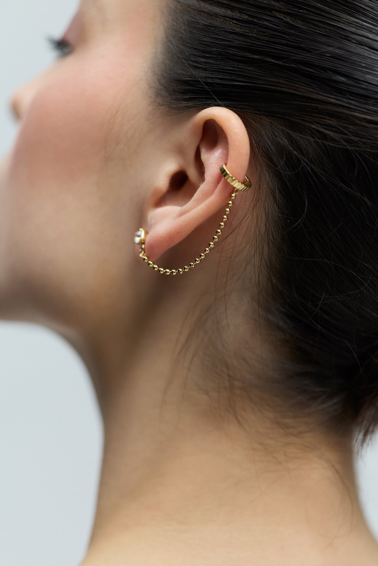 CLOSE UP OF THE BACK OF A MODEL’S EAR, WEARING THE DELANCEY SINGLE SWAG CUFF EARRINGS