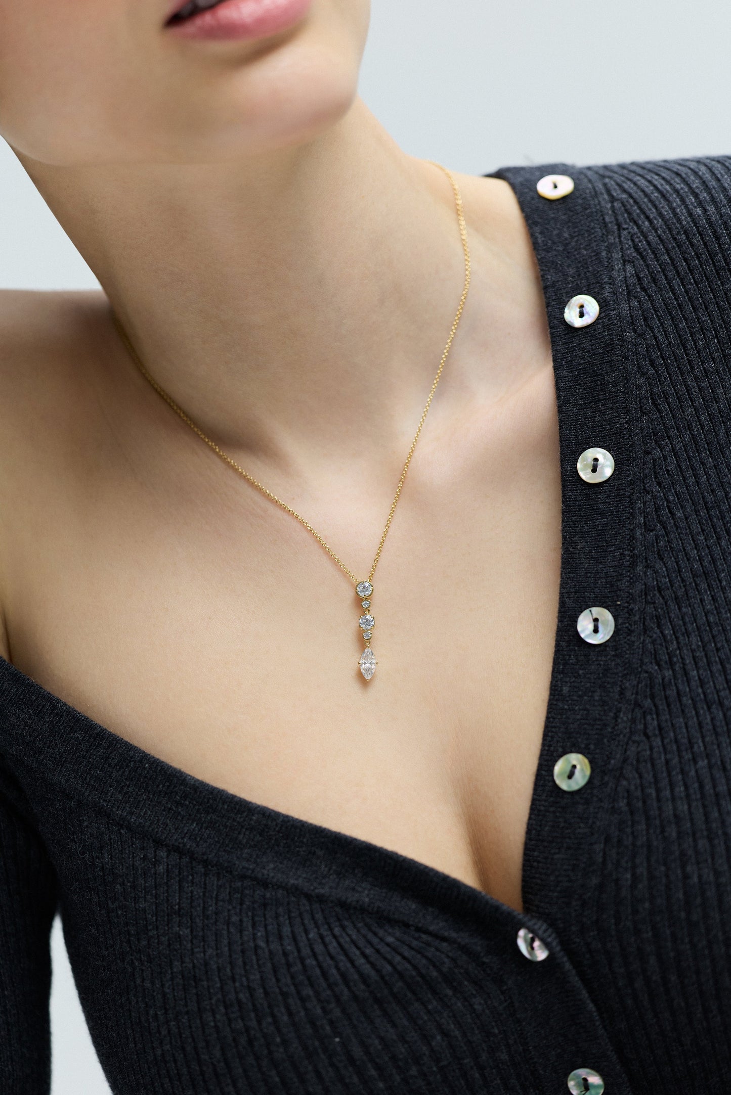 CLOSE UP OF A MODEL’S CHEST WEARING A GRAY SWEATER AND THE DELANCEY SHORT Y NECKLACE, AS SHE SLIGHTLY LEANS TO THE SIDE