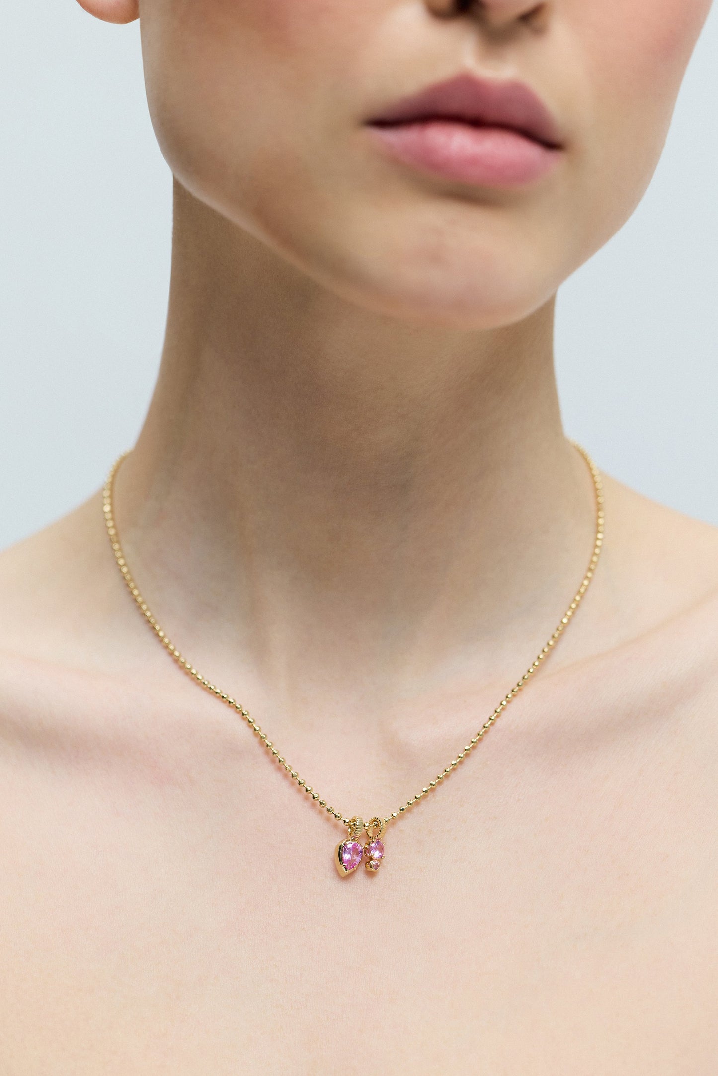 CLOSE UP OF A MODEL’S CHEST WEARING THE DELANCEY PINK CHARM PENDANT NECKLACE