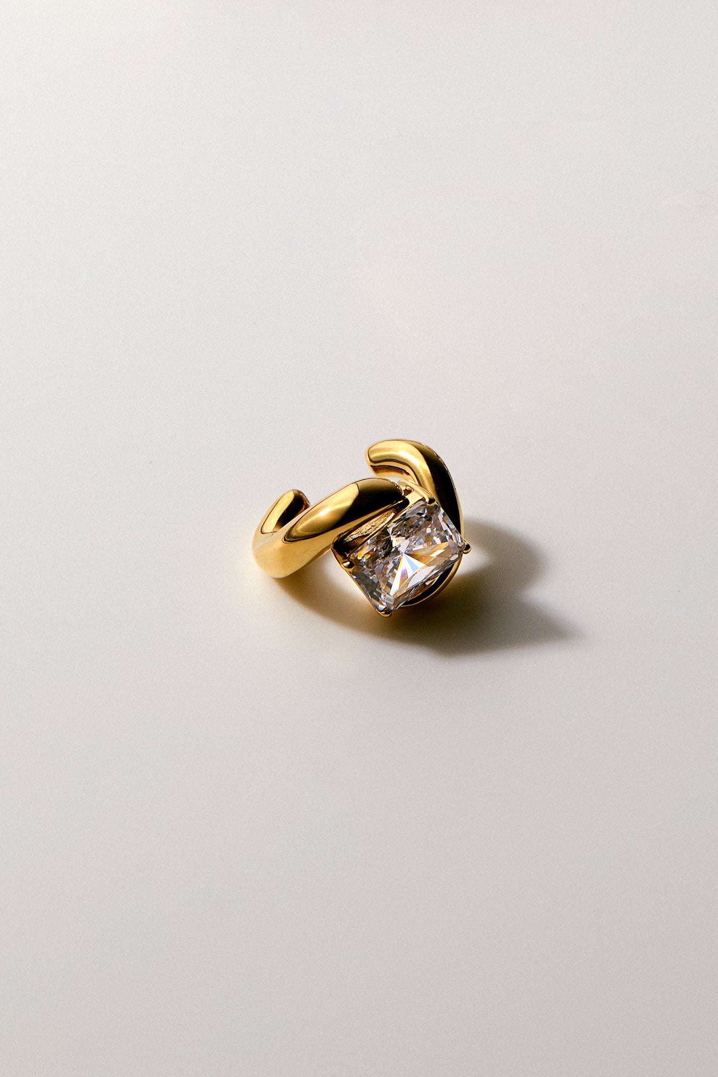 Close up shot of the Phenom Single Emerald Cuff Earring with a slight shadow.
