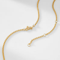 A gold chain necklace that says "Slay" with two cubic zirconia stones