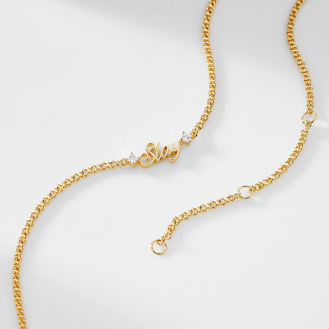 A gold chain necklace that says "Slay" with two cubic zirconia stones