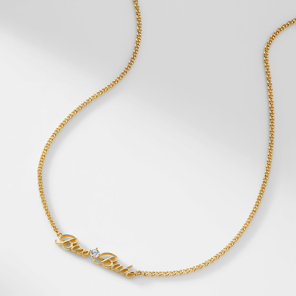 A gold chain necklace that says "Boss Babe" with a single cubic zirconia stone
